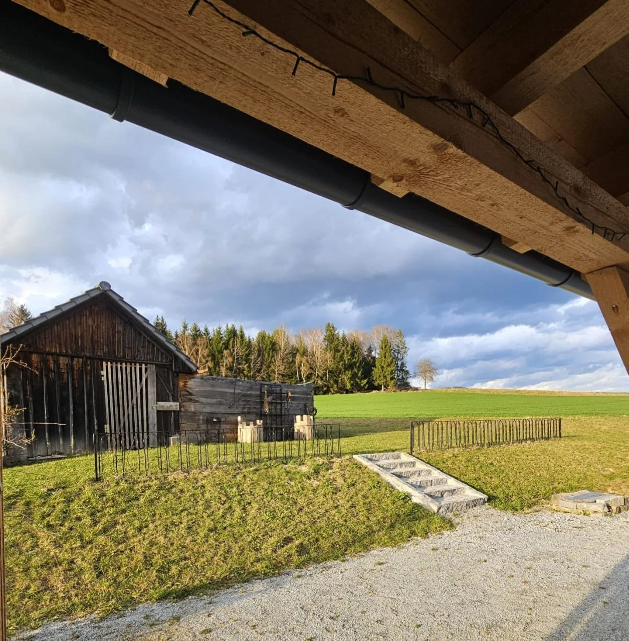 Blick von der Pergola auf einen alten Holzstadel und die Felder am Ferienhaus im Böhmerwald