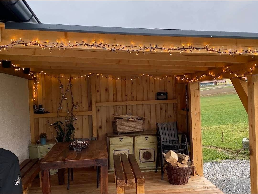 Überdachte Pergola mit Holztisch, Bänken und Lichterketten am Ferienhaus im Böhmerwald
